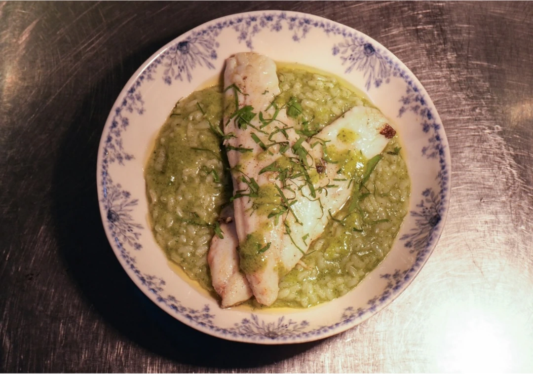 Filetes de peixe sobre arroz de coentros, num prato de louça antiga