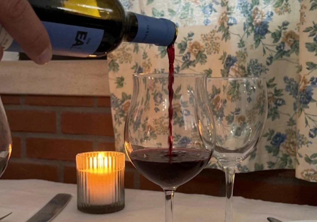 Vinho tinto a ser servido à mesa, com vela acesa